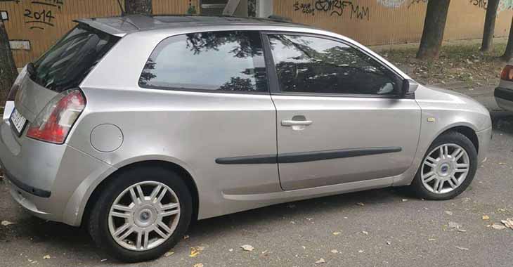 Desni bočni prikaz sivog automobila Fiat Stilo na parkingu